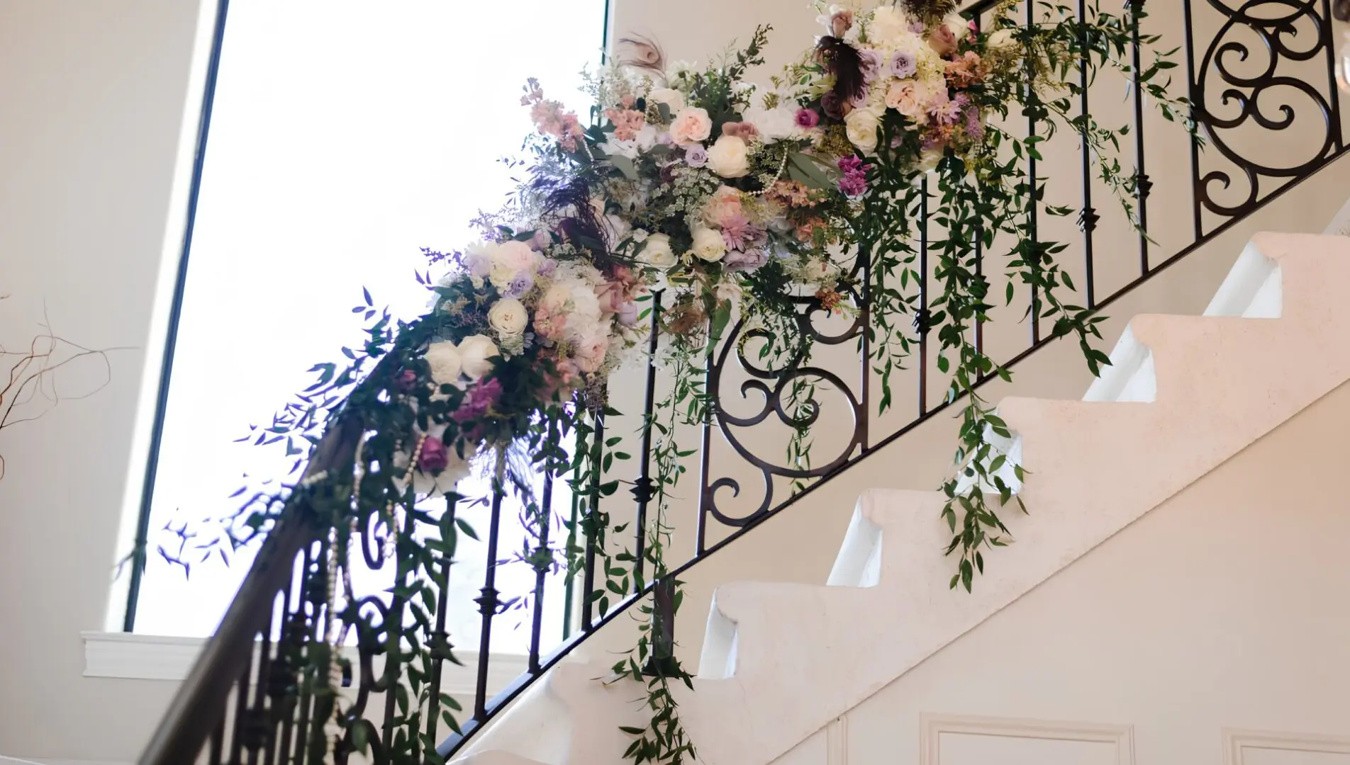 A staircase with flowers and vines on the railing.