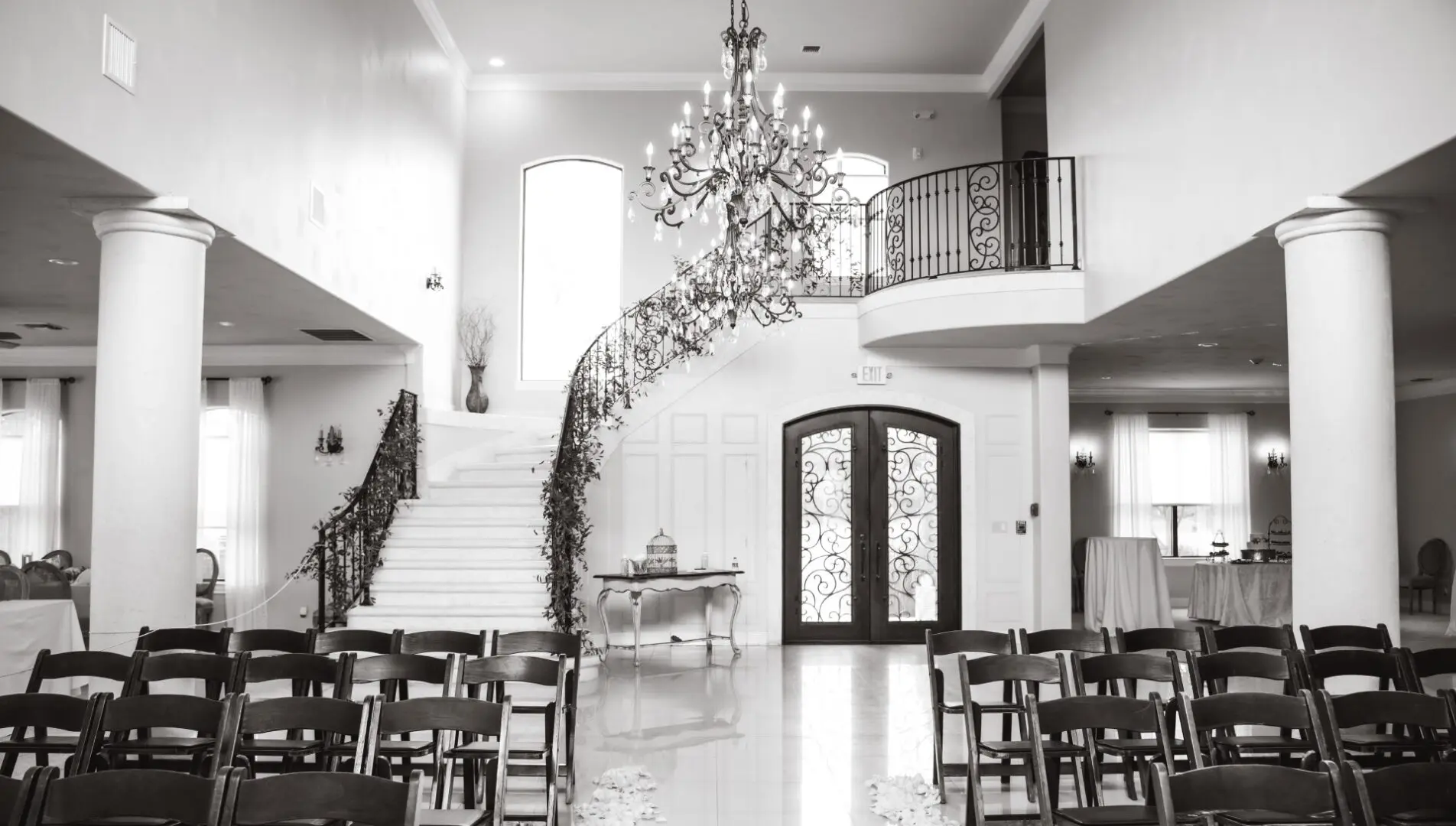 A large room with two sets of chairs and a chandelier.