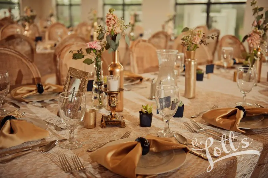 A table set with plates and silverware, napkins, glasses and vases.