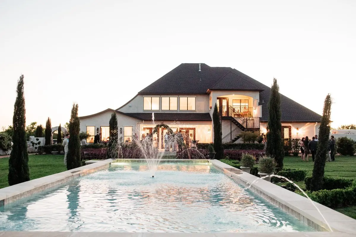 A large pool in front of a house with water jets.