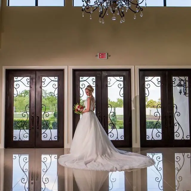 A bride in her wedding dress standing inside of the room.