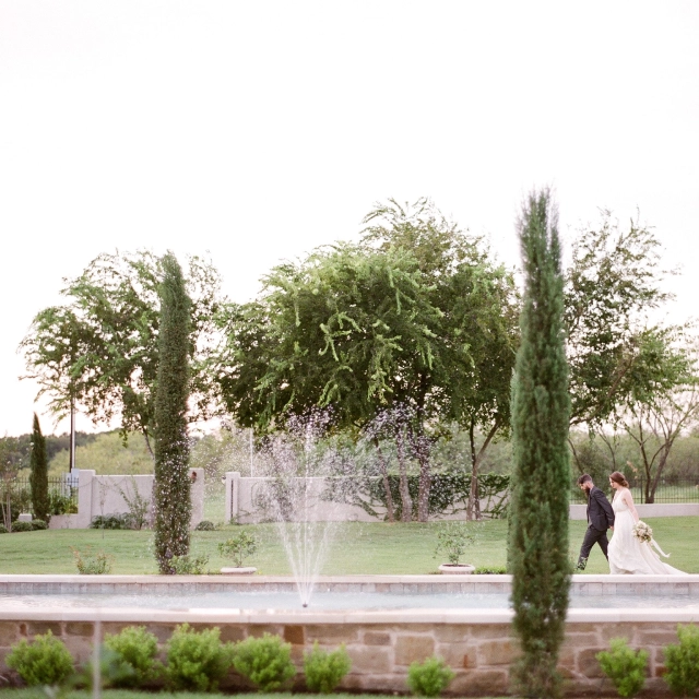 A couple walking in front of a fountain.