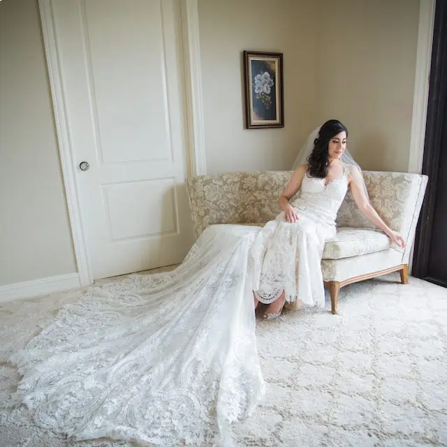 A bride sitting on the couch in her wedding dress.