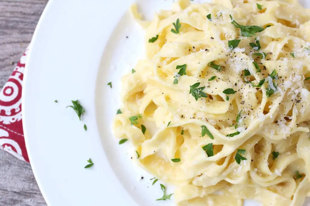 A plate of pasta with cheese and parsley.